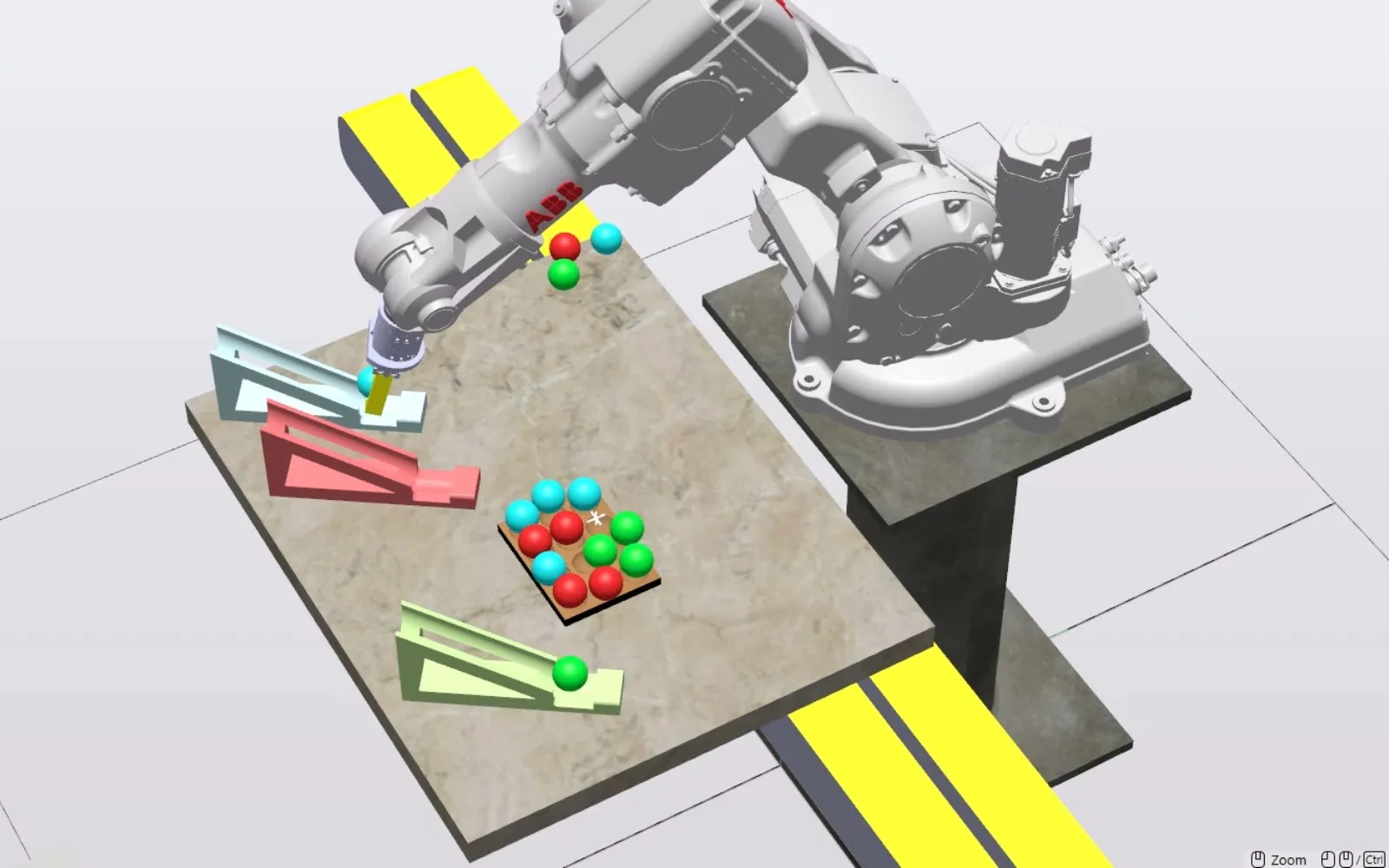 Simulated ABB robot in RobotStudio placing red, green, and blue balls on a cardboard tray, with three colored ramps on the table.